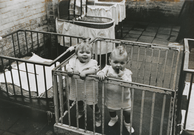 876979 Afbeelding van twee kindertjes in een box op de binnenplaats van het opvanghuis 'Meisjesstad' (Oudegracht 35) ...